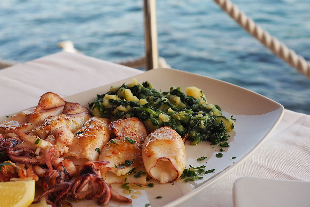 Grilled squid with boiled potatoes and chard (blitva) on white p